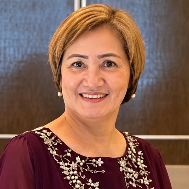 Milagros Arora smiling in a maroon beaded dress
